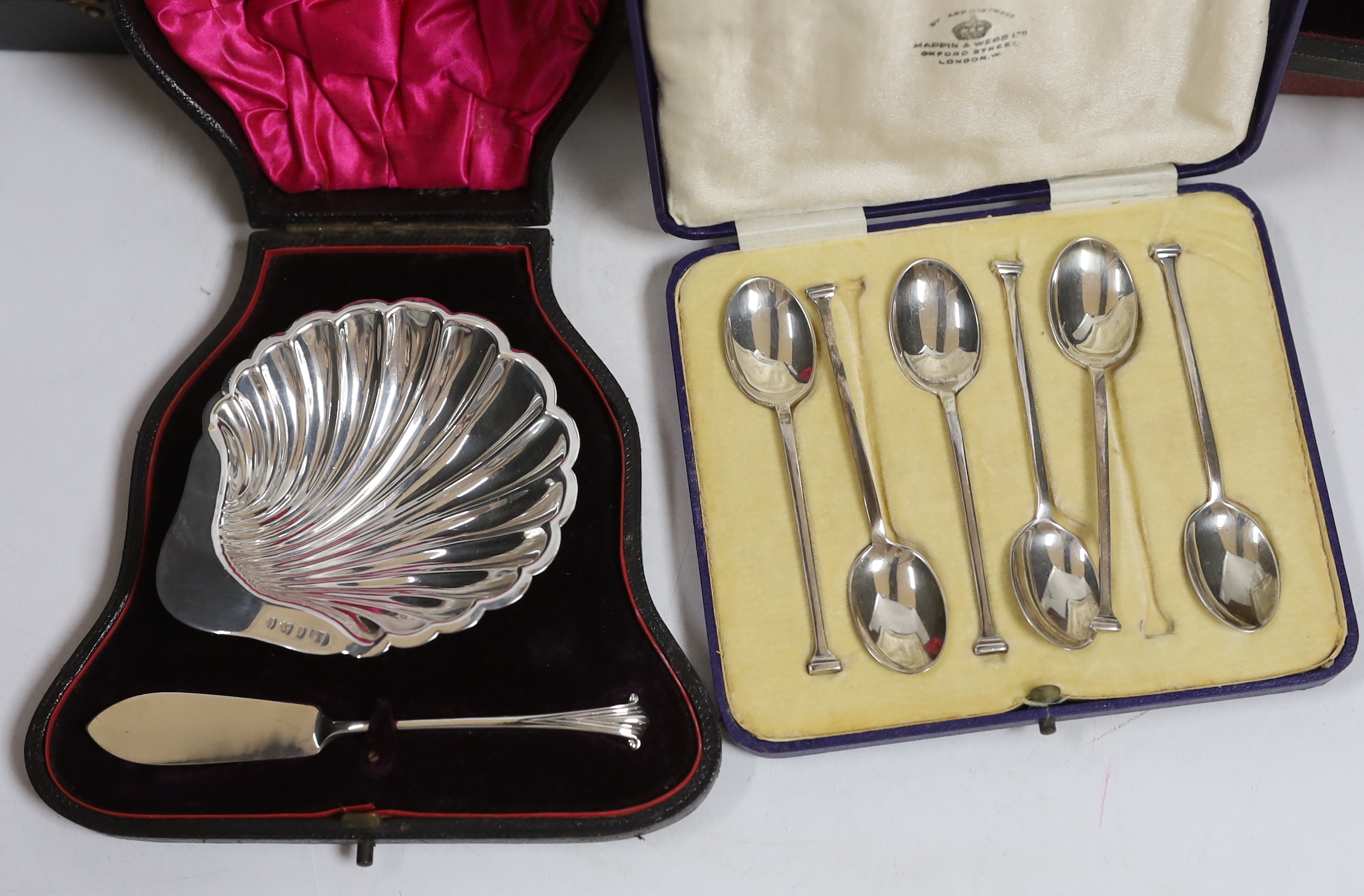 Two modern silver cased shell and butter knife sets, a cased silver five piece condiment set, a cased set of six silver teaspoons with tongs, one other cased silver butter shell and knife and a cased set of plated teaspo